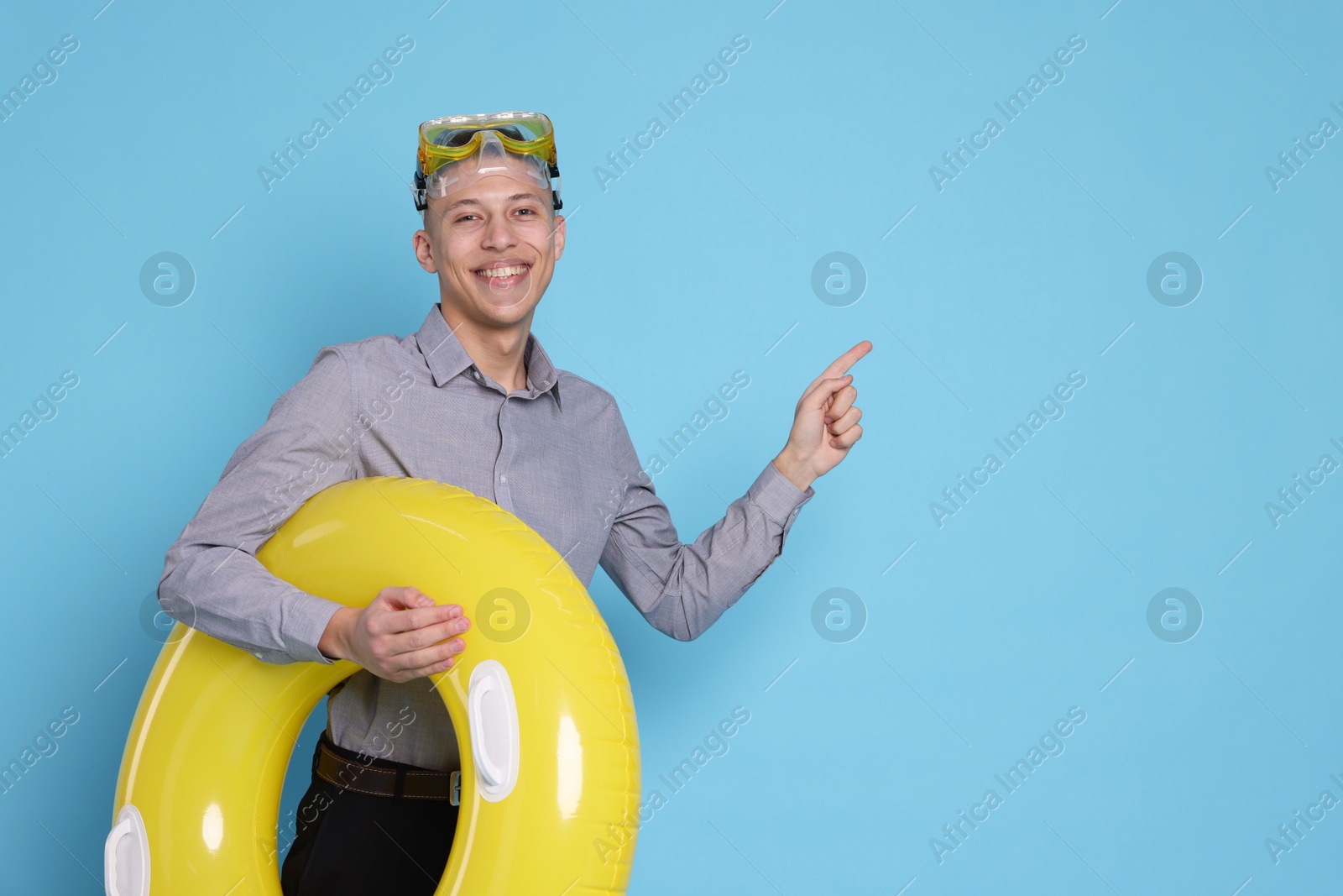 Photo of Businessman with inflatable ring and diving mask on light blue background, space for text