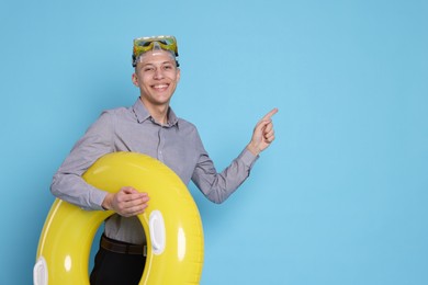 Photo of Businessman with inflatable ring and diving mask on light blue background, space for text