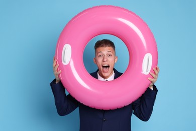 Photo of Businessman with inflatable ring on light blue background