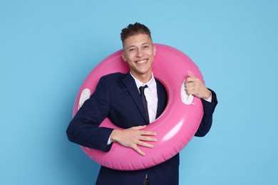 Photo of Businessman with inflatable ring on light blue background