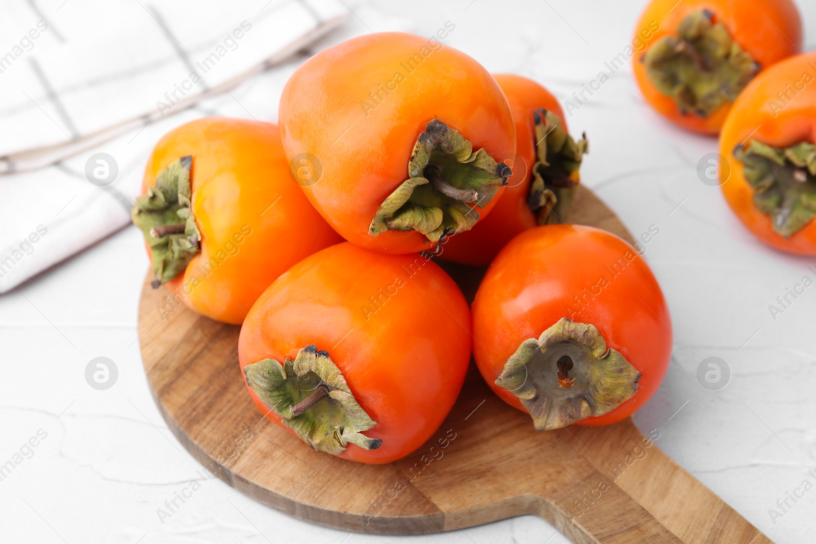 Photo of Delicious fresh juicy persimmons on white table, closeup