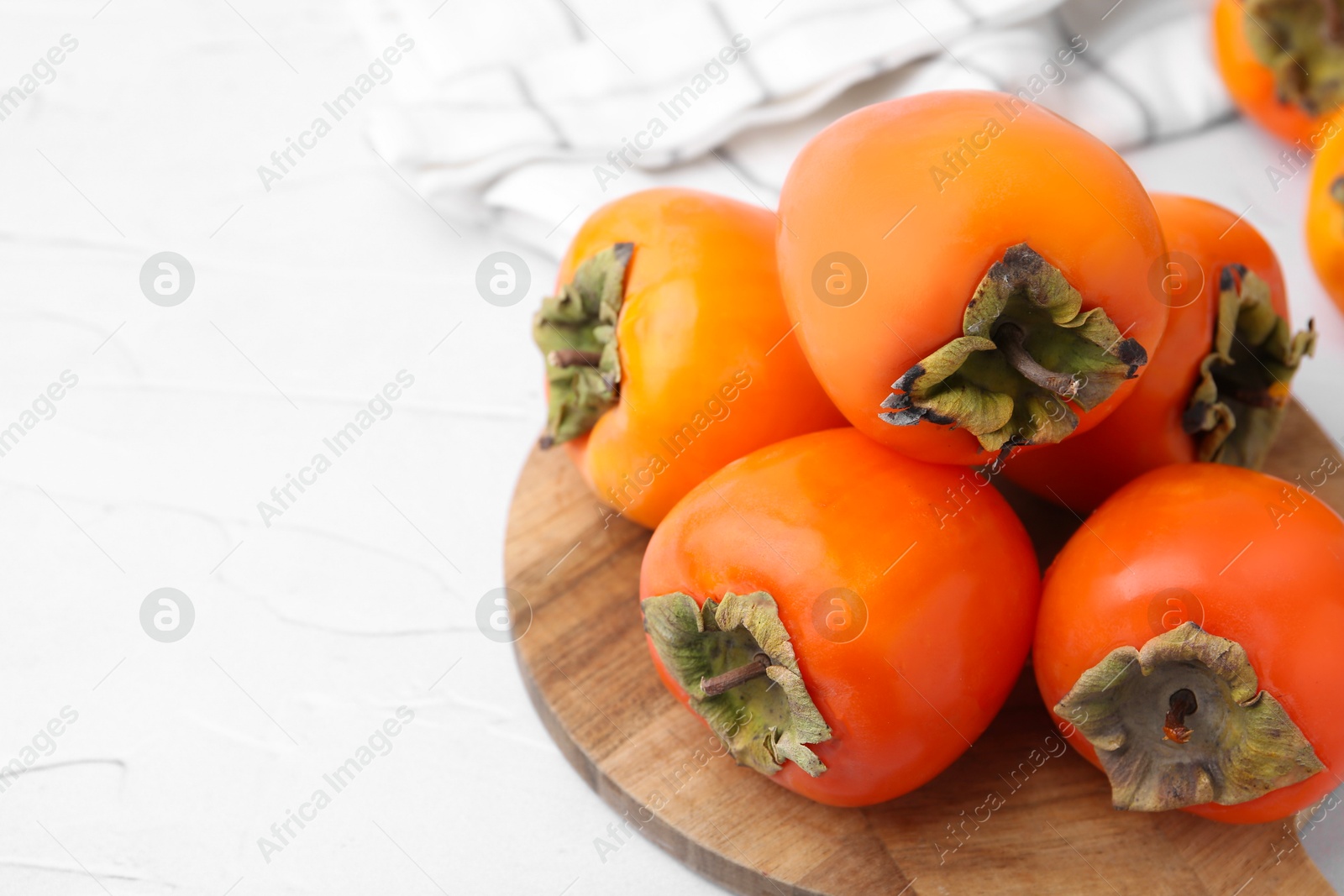 Photo of Delicious fresh juicy persimmons on white table, closeup. Space for text