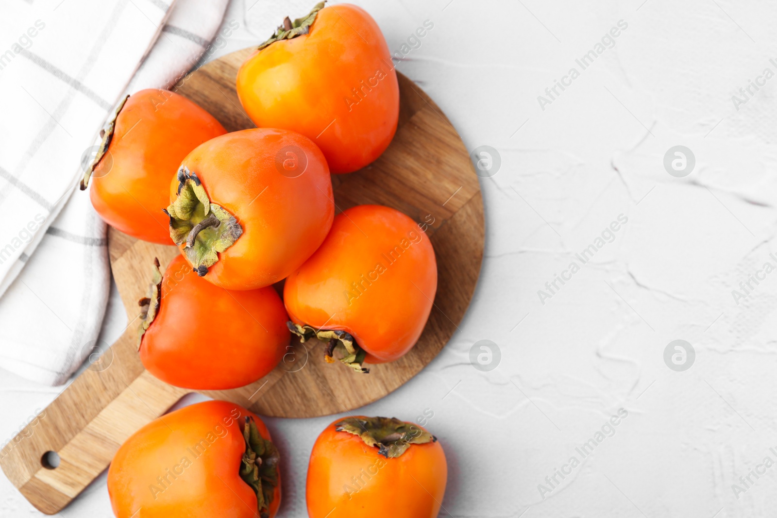 Photo of Delicious fresh juicy persimmons on white table, top view. Space for text