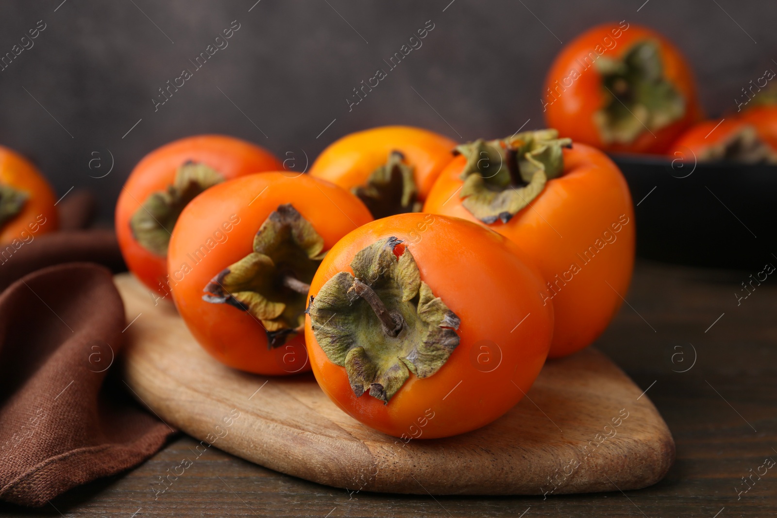 Photo of Delicious fresh juicy persimmons on wooden table, closeup