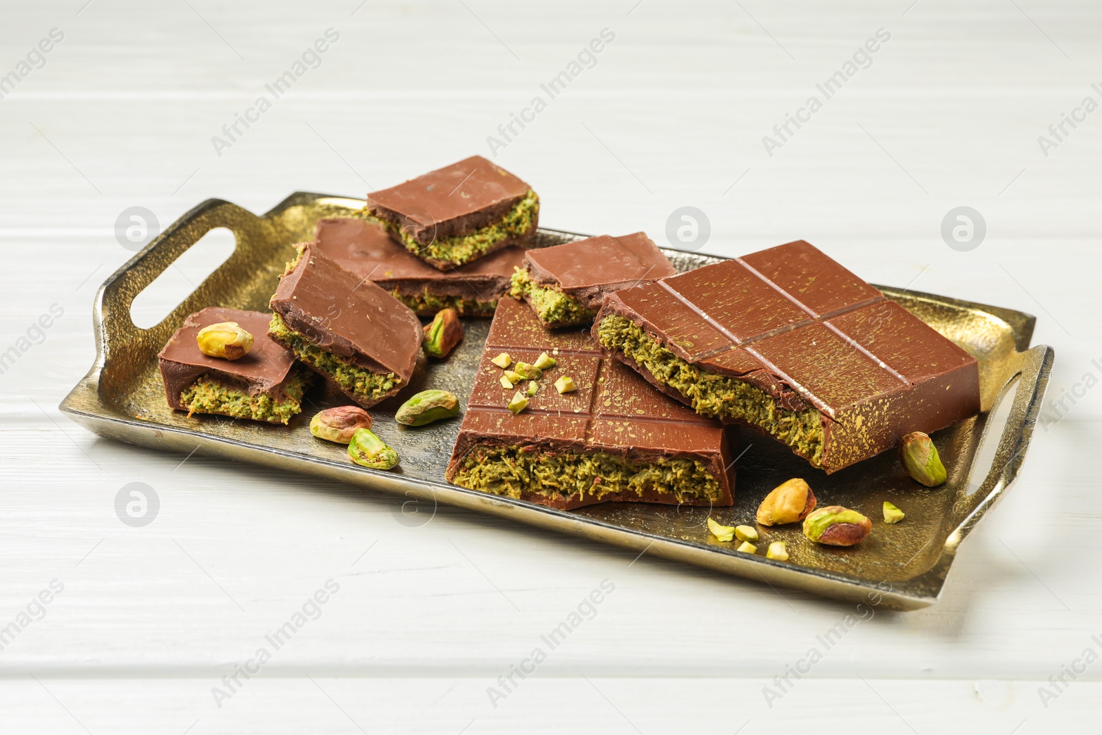 Photo of Pieces of Dubai chocolate bars with pistachios and knafeh on white wooden table