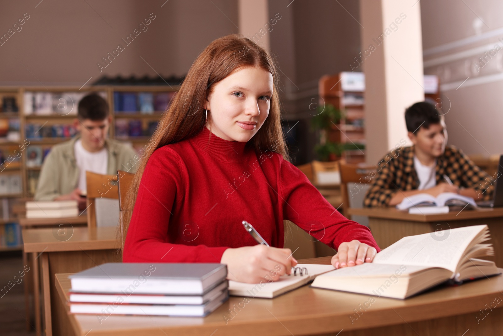 Photo of Girl taking notes at desk in public library