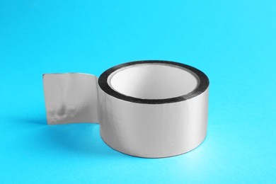 Photo of Roll of silver adhesive tape on light blue background