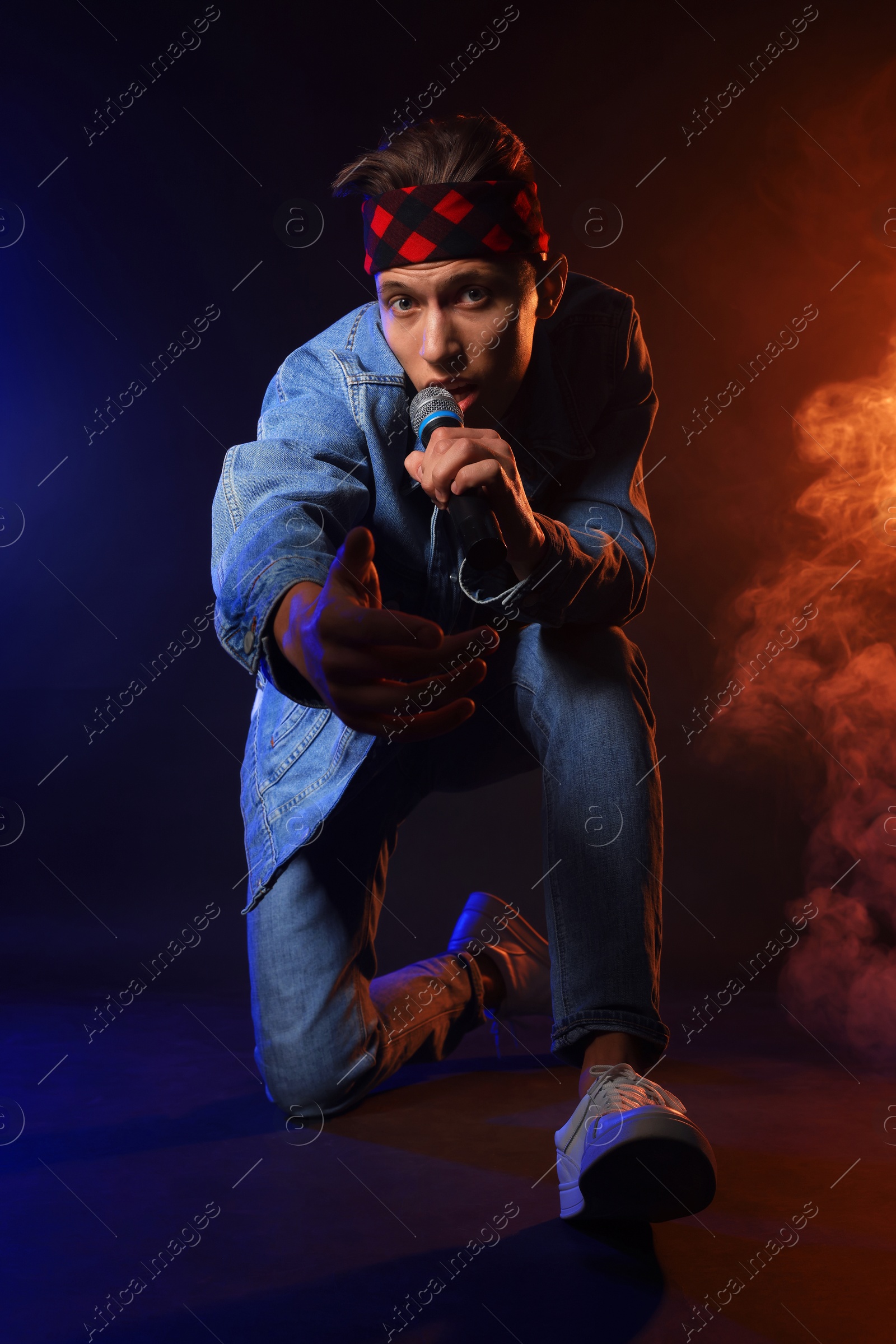 Photo of Talented singer performing on dark background with color lights