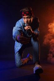 Photo of Talented singer performing on dark background with color lights