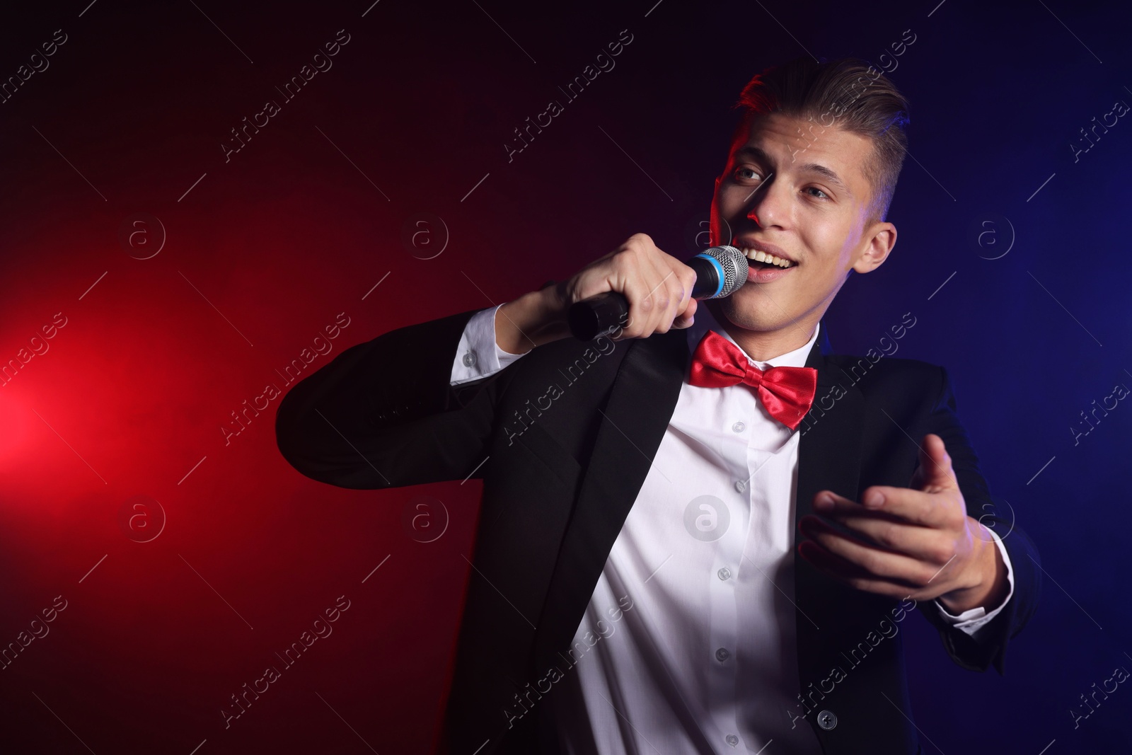 Photo of Talented singer performing on dark background with color lights