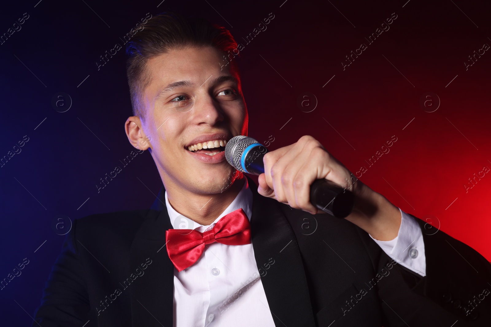 Photo of Talented singer performing on dark background with color lights