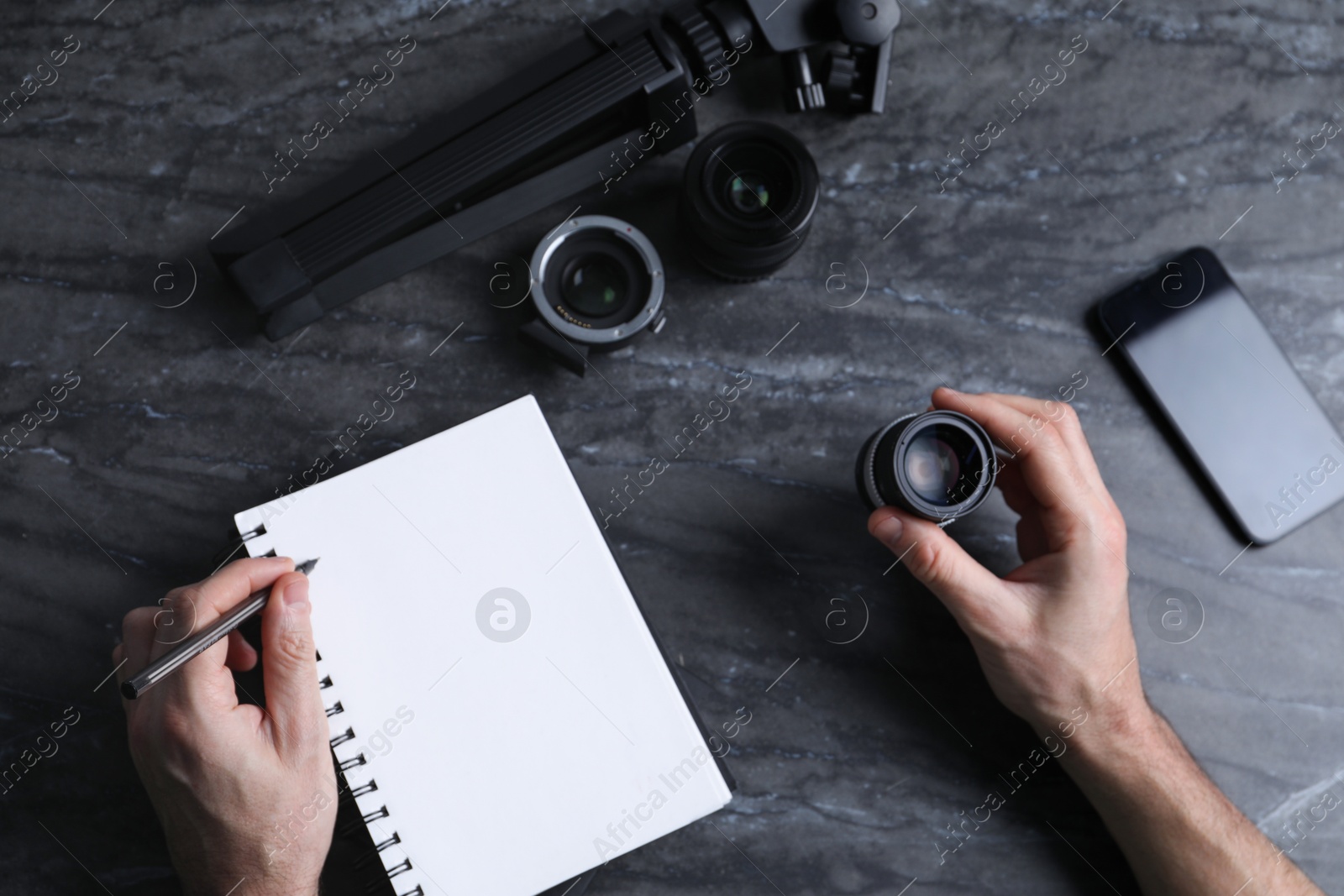 Photo of Photographer with camera lens, pen and notebook at gray marble table, top view