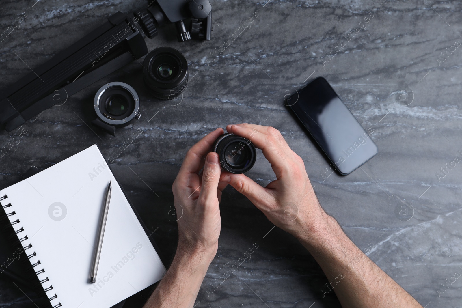 Photo of Photographer with camera lens at gray marble table, top view