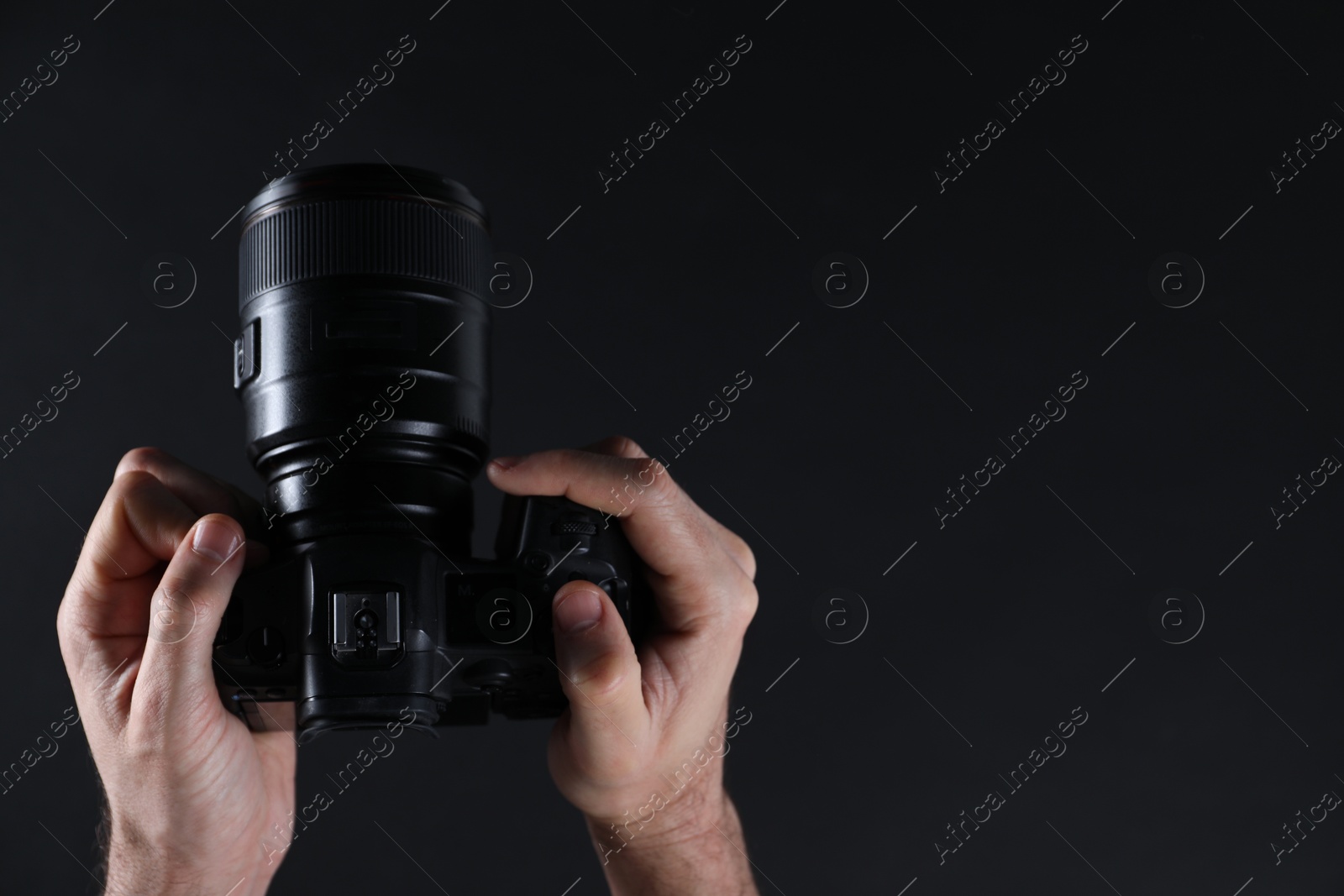 Photo of Photographer with professional camera on dark background, closeup. Space for text