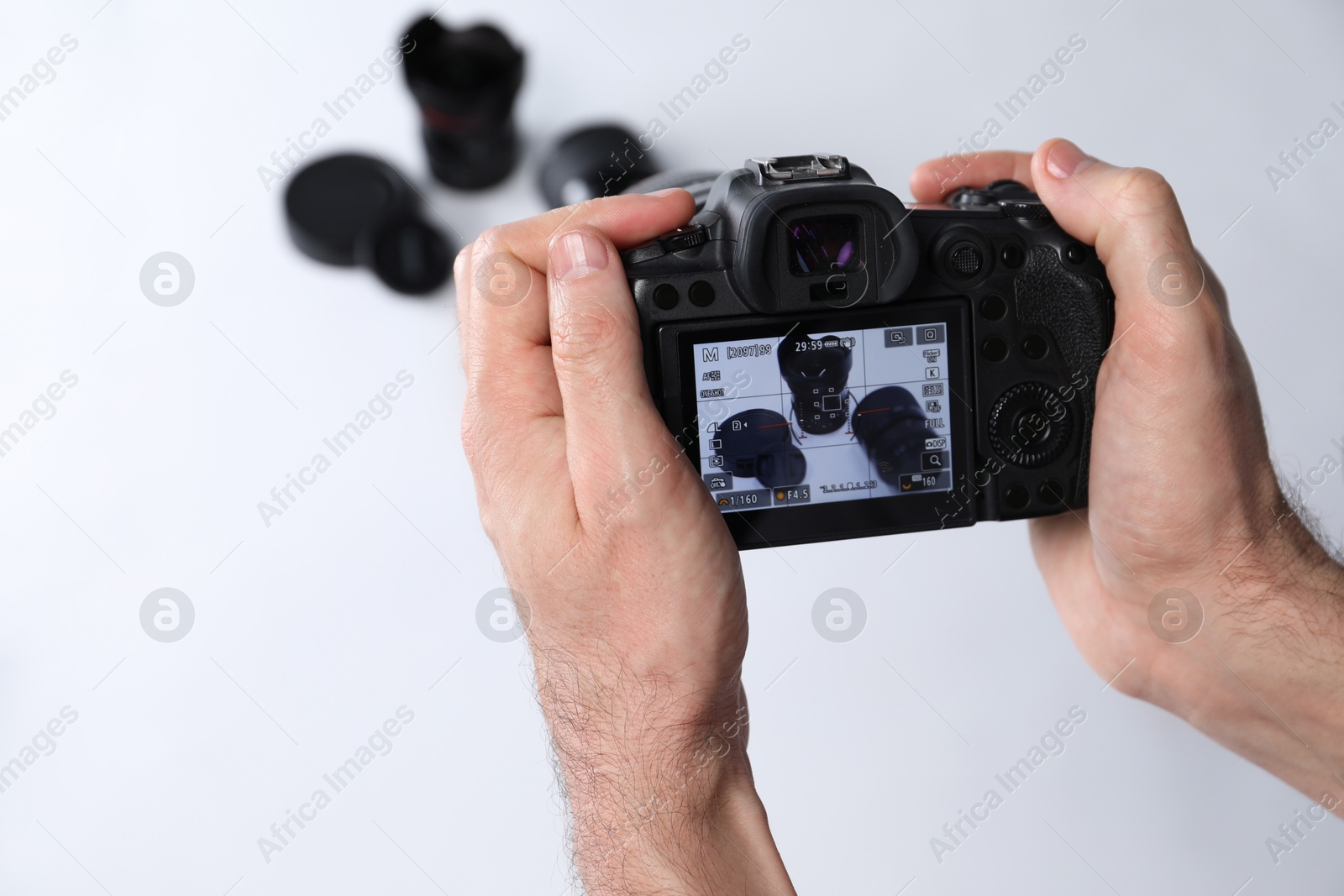 Photo of Photographer taking photo with professional camera on white background, closeup. Space for text