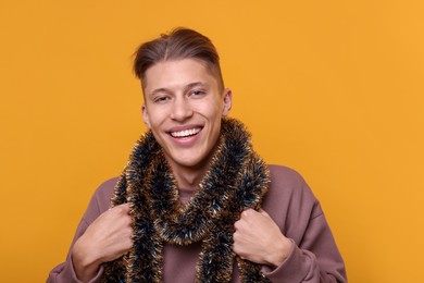 Photo of Happy young man with tinsel on orange background