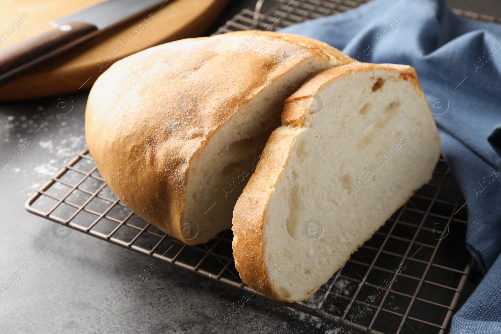 Photo of Cut fresh bread and knife on grey table, closeup