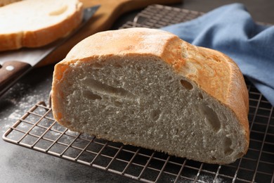 Photo of Cut fresh bread and knife on grey table, closeup