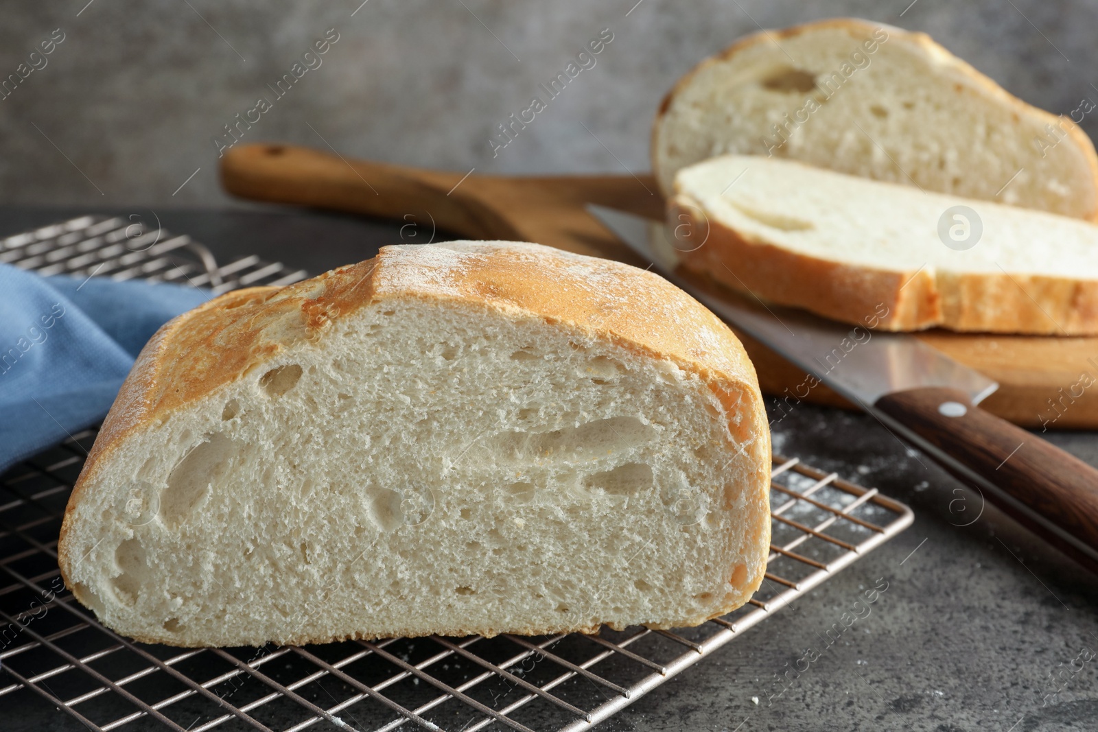 Photo of Cut fresh bread and knife on grey table, closeup