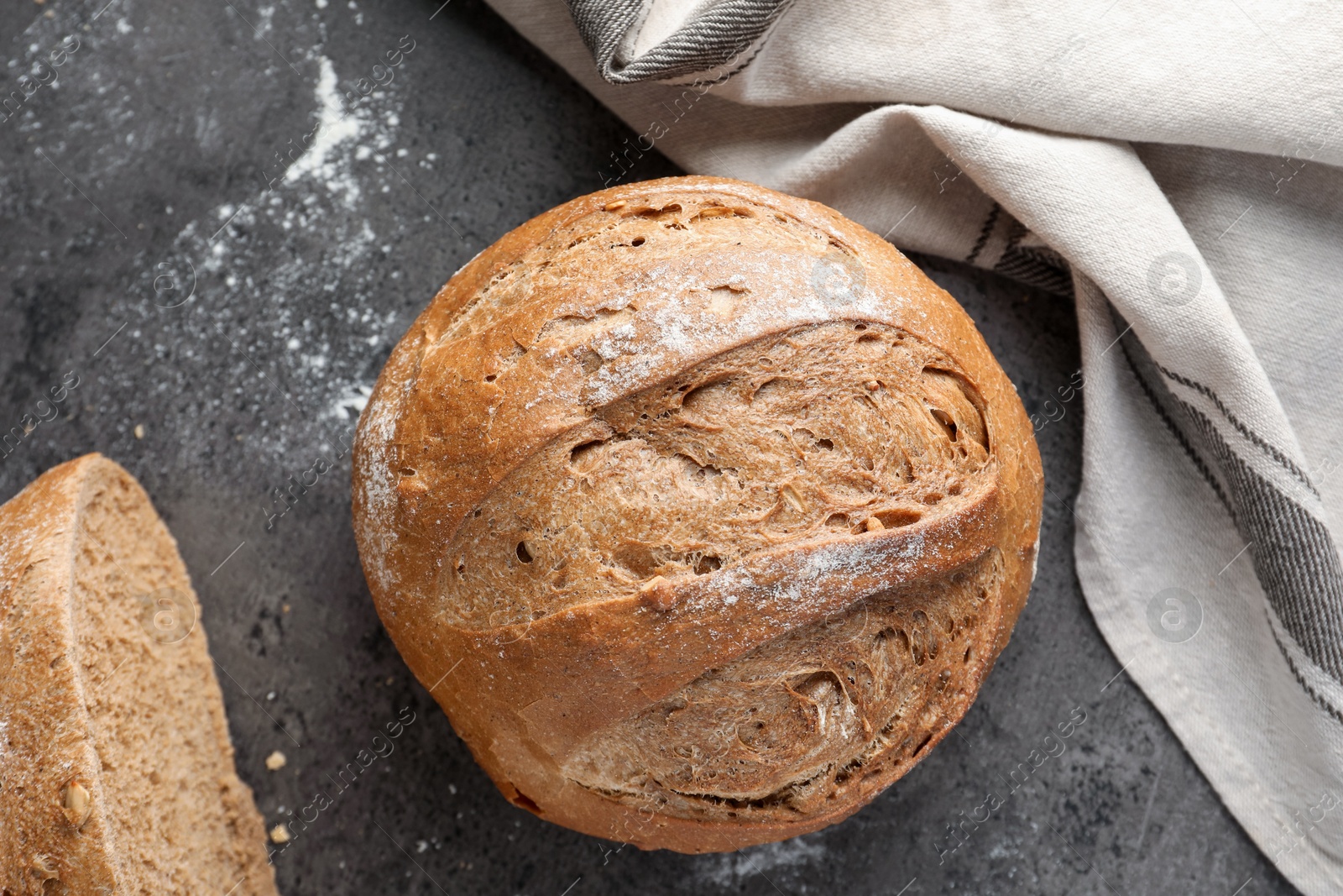 Photo of Whole and cut fresh bread on grey table, top view