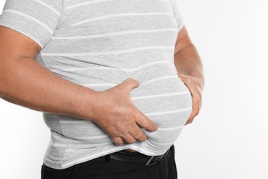 Photo of Overweight man in tight t-shirt on white background, closeup