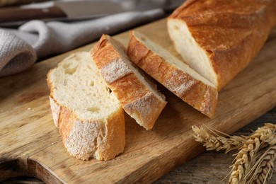 Photo of Pieces of fresh baguette and spikes on wooden table, closeup