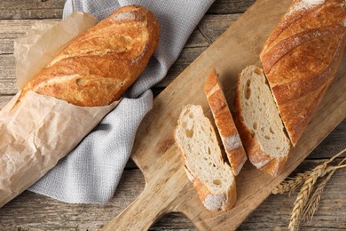 Photo of Fresh baguettes and spikes on wooden table, flat lay