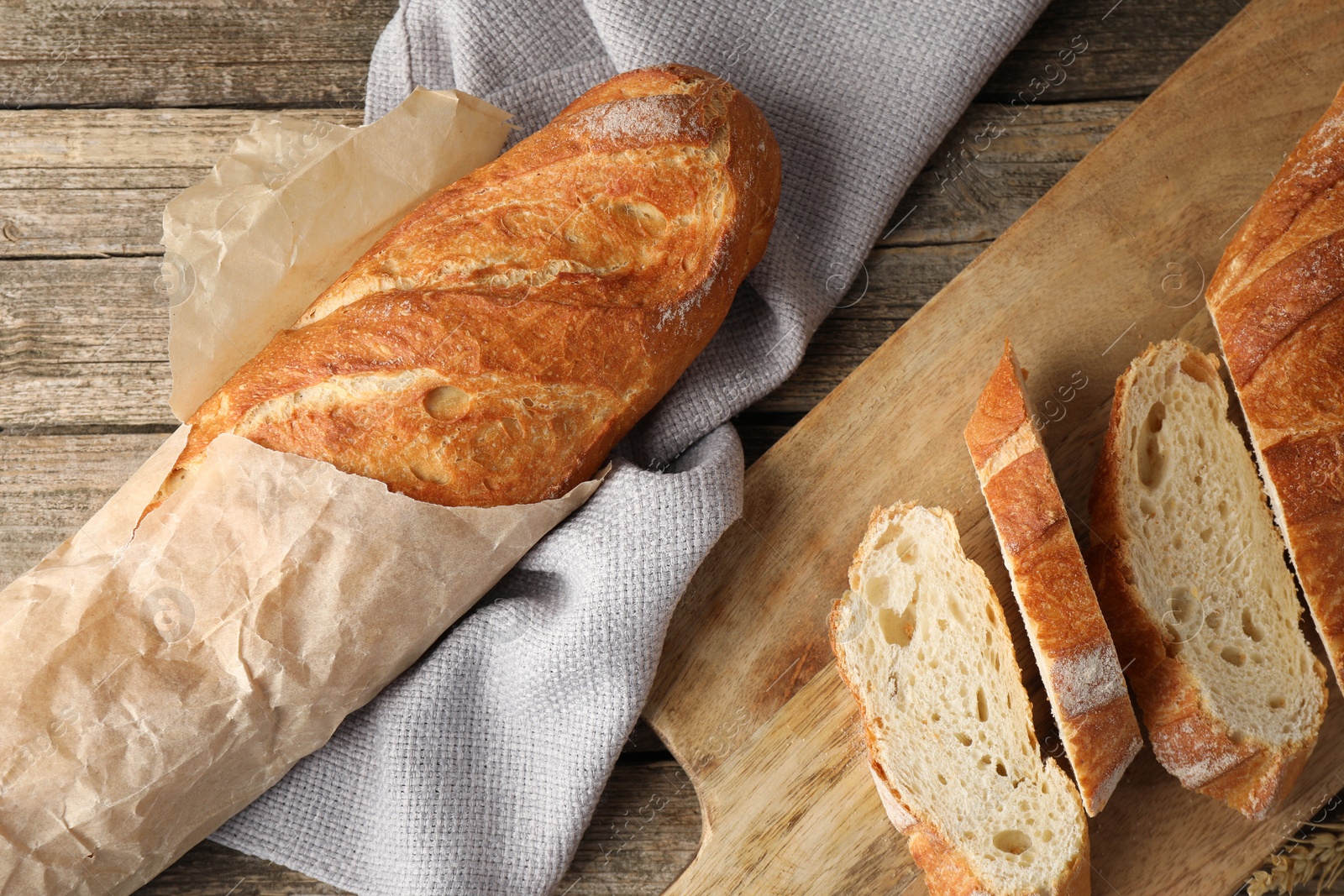 Photo of Whole and cut fresh baguettes on wooden table, top view