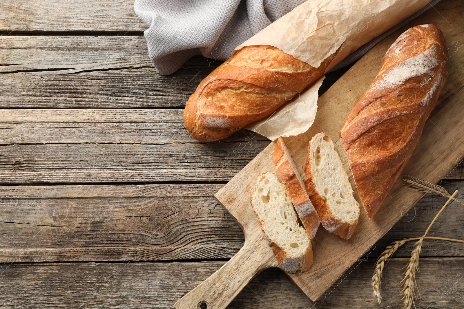 Photo of Fresh baguettes and spikes on wooden table, flat lay. Space for text