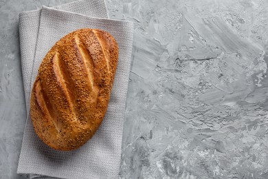 Photo of Freshly baked bread with seeds on grey table, top view. Space for text