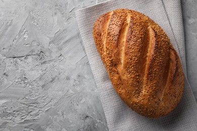 Photo of Freshly baked bread with seeds on grey table, top view. Space for text