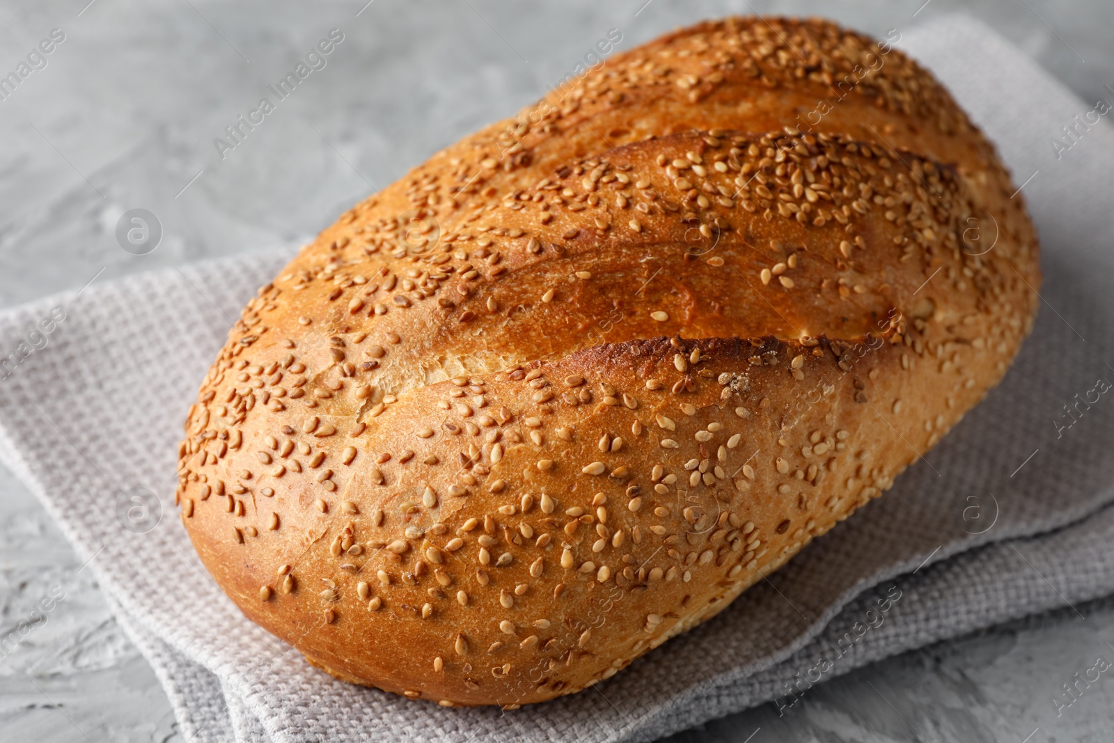 Photo of Freshly baked bread with seeds on grey table, closeup