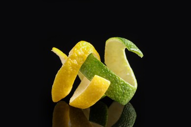 Photo of Lemon and lime peels on black glass surface, closeup