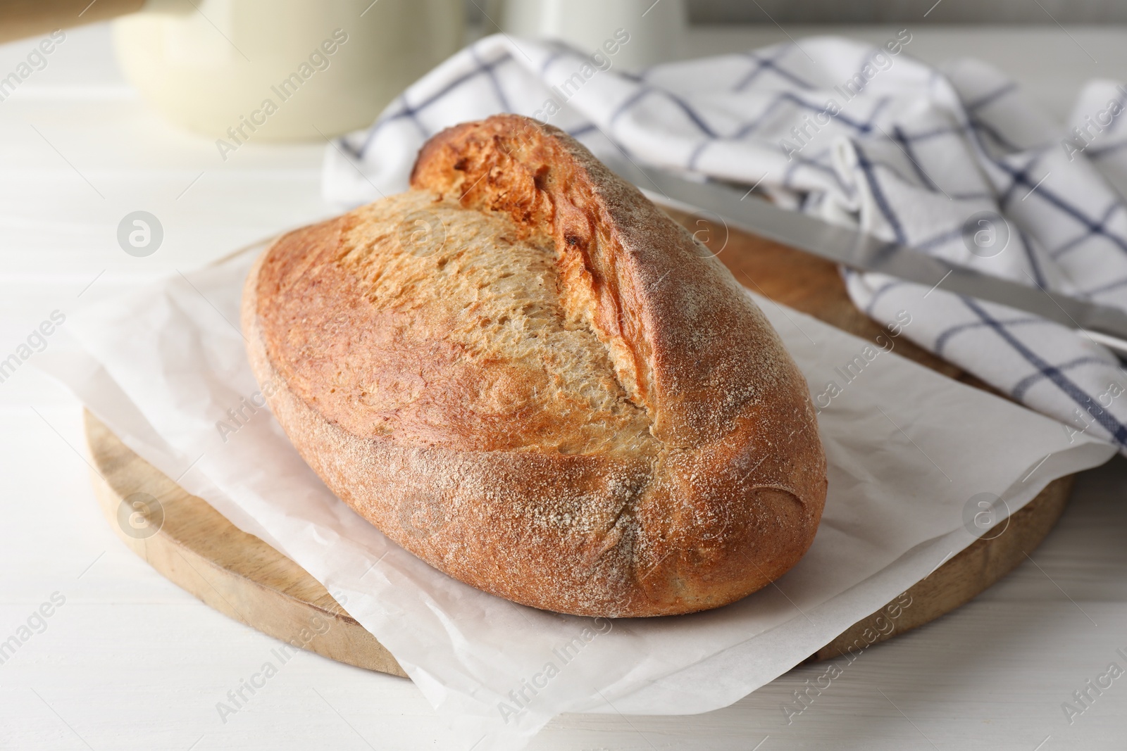 Photo of Loaf of delicious bread on white wooden table, closeup