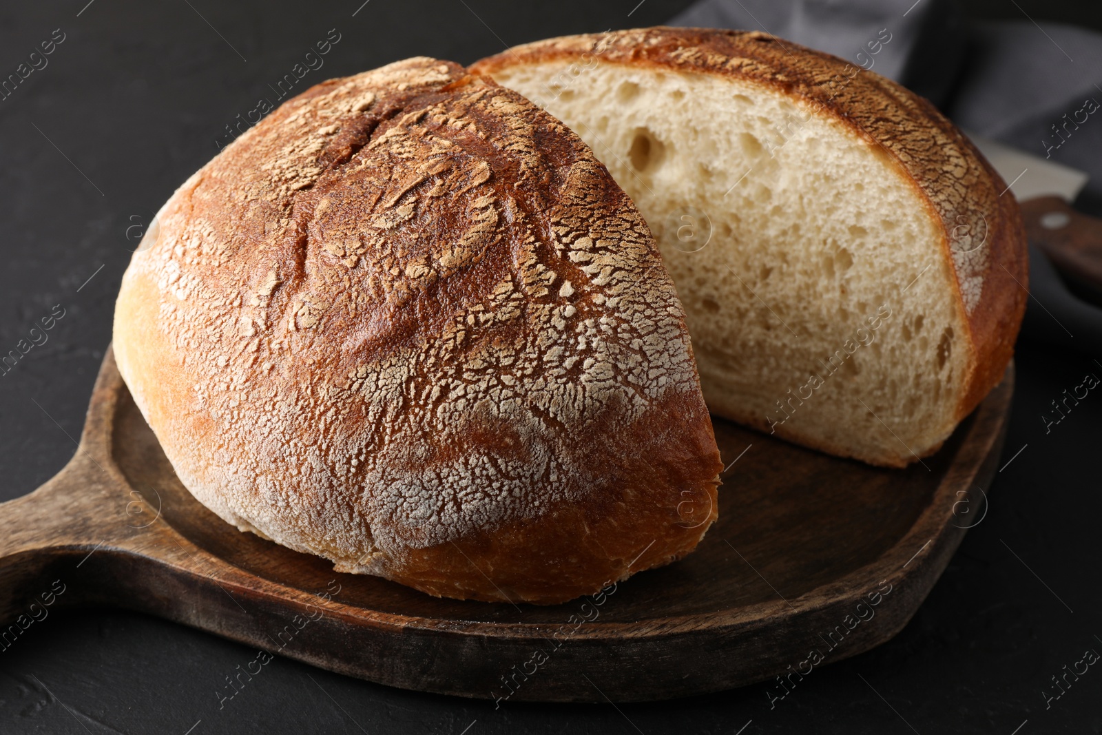 Photo of Cut loaf of bread on black table, closeup