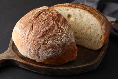 Photo of Cut loaf of bread on black table, closeup