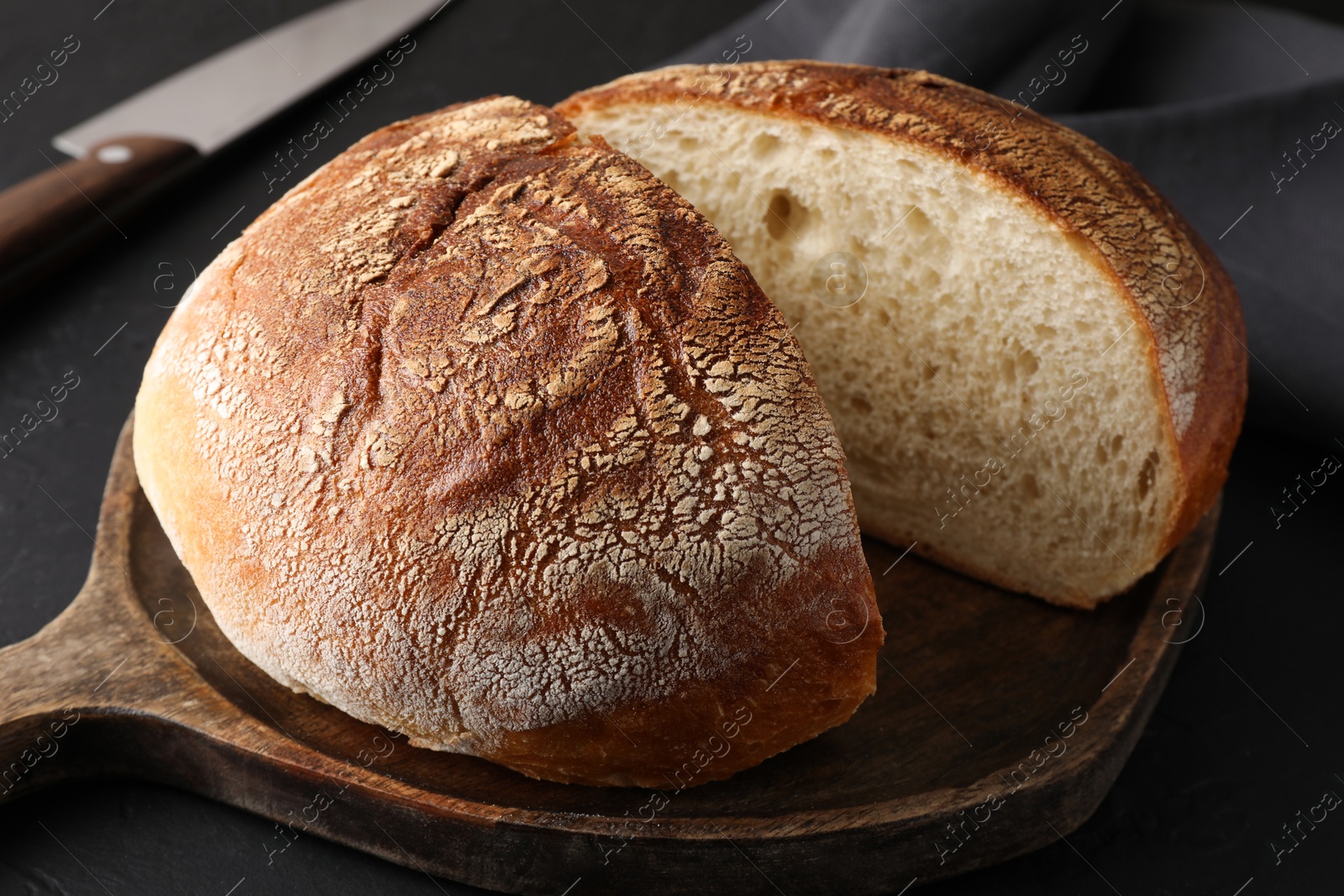 Photo of Cut loaf of bread on black table, closeup