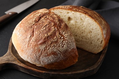 Photo of Cut loaf of bread on black table, closeup