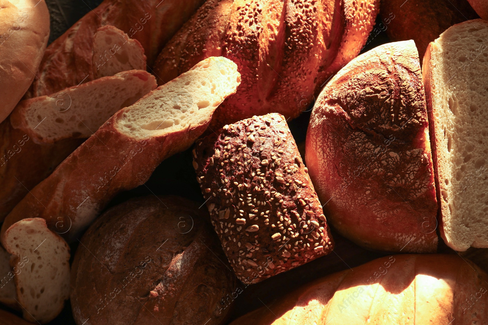 Photo of Whole and cut loafs of bread on table, closeup