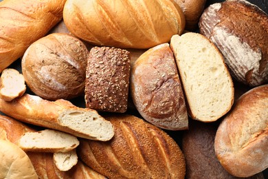 Photo of Whole and cut loafs of bread on table, closeup