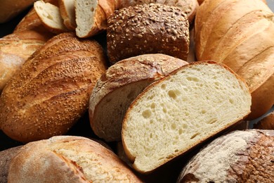 Photo of Whole and cut loafs of bread on table, closeup