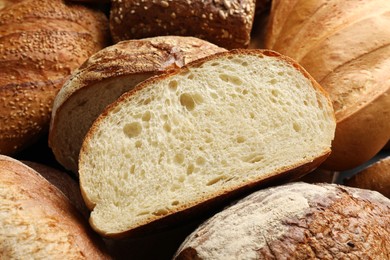 Photo of Whole and cut loafs of bread on table, closeup