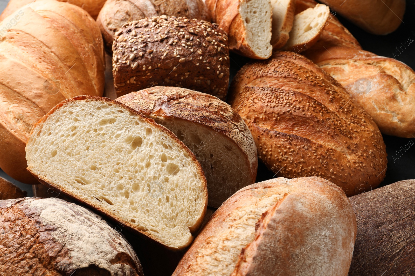 Photo of Whole and cut loafs of bread on table, closeup