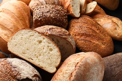 Photo of Whole and cut loafs of bread on table, closeup