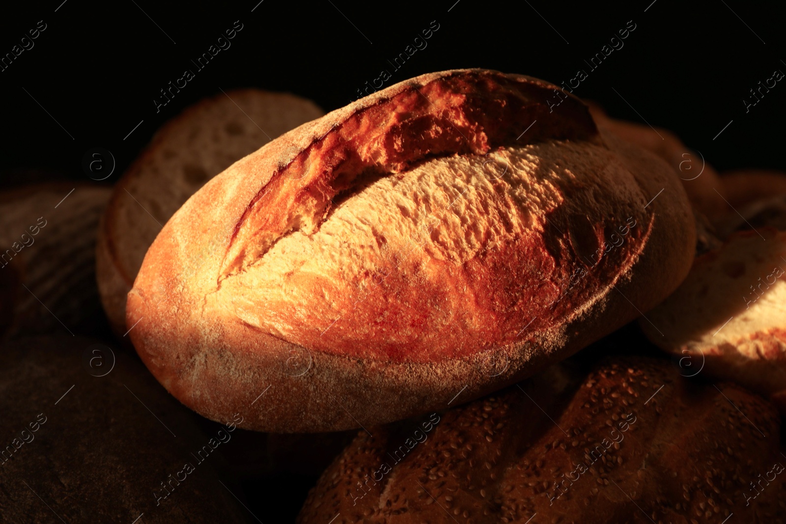 Photo of Loaf of crusty bread on dark background, closeup