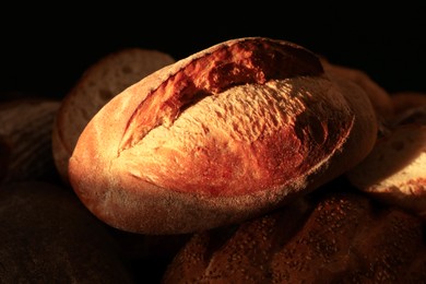 Photo of Loaf of crusty bread on dark background, closeup