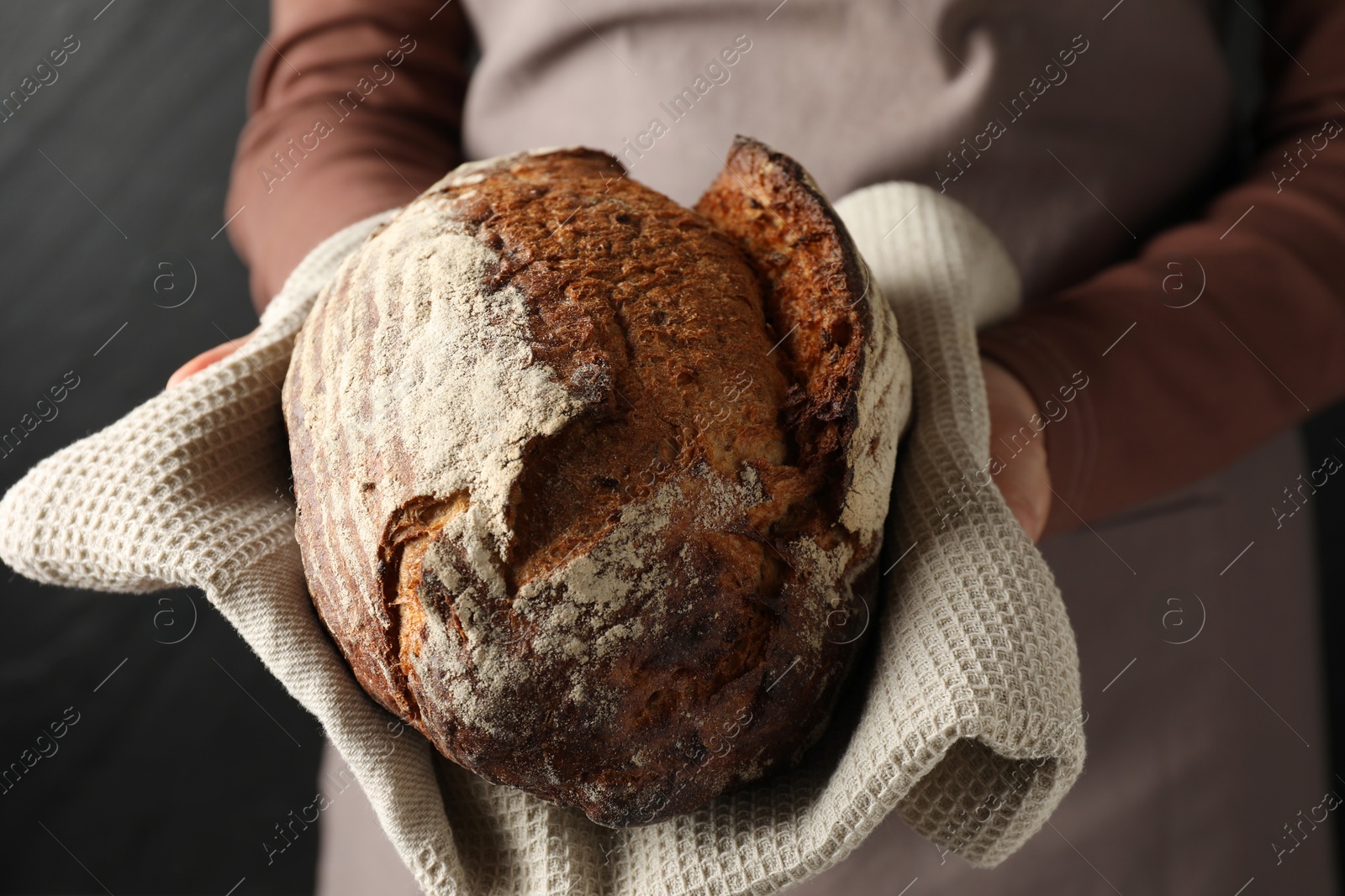 Photo of Woman with loaf of freshly baked bread on black background, closeup