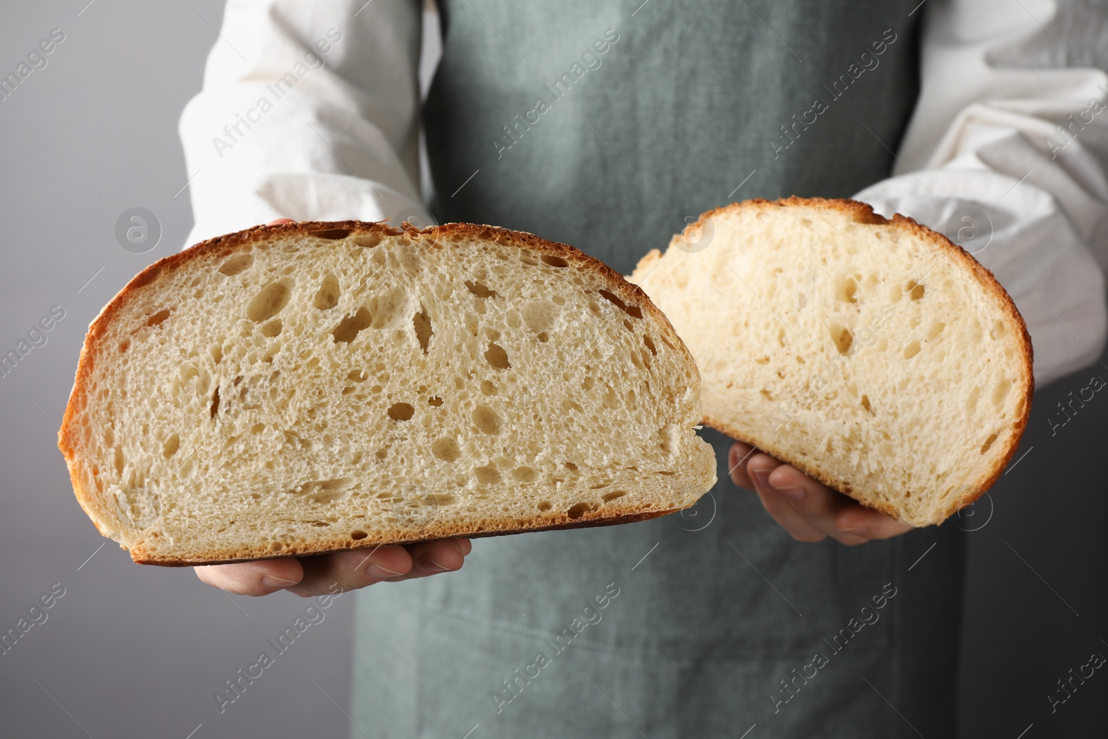 Photo of Woman with pieces of fresh bread on grey background, closeup