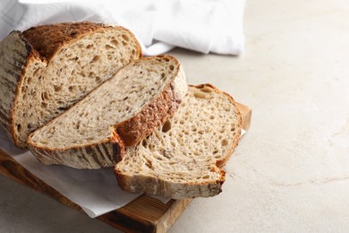 Photo of Cut loaf of fresh bread on table, closeup