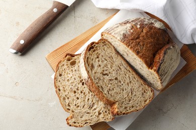 Photo of Cut loaf of fresh bread and knife on table, top view